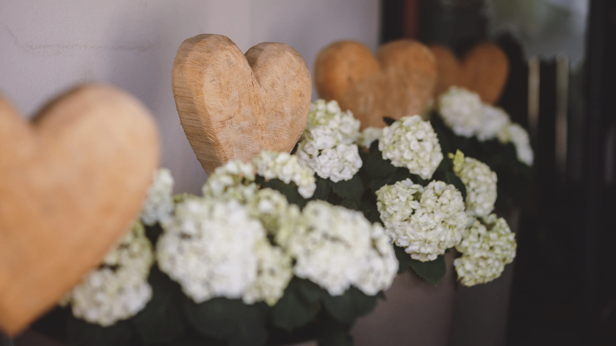 Holzherzen neben blühenden weißen Blumen