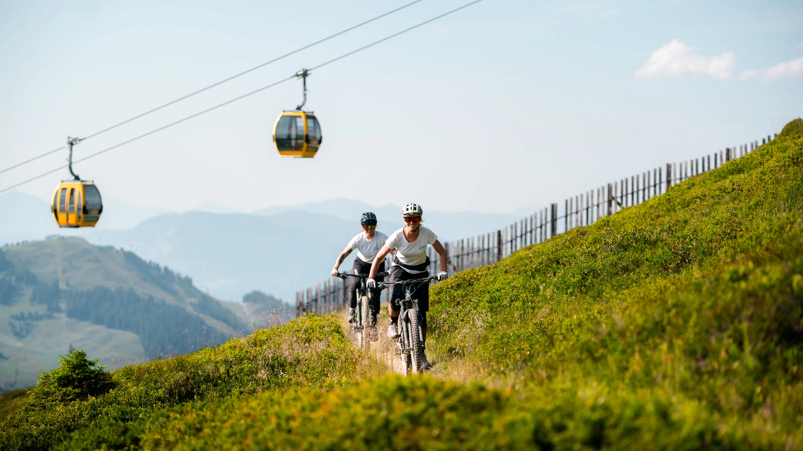 Zwei Radfahrer in den Bergen mit Gondelbahn im Hintergrund