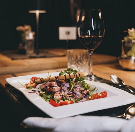 Ein Teller mit Salat und Wein auf einem Tisch.