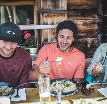 Drei Männer essen bei einer Wanderpause in Saalbach-Hinterglemm
