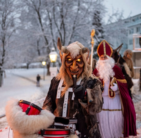 Maskierte Person mit Schlagzeug in verschneiter Winterlandschaft
